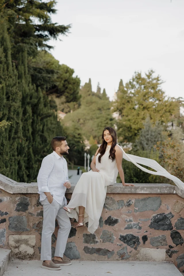 Abdulrahman holding Natalie's hand as she sits on a garden wall